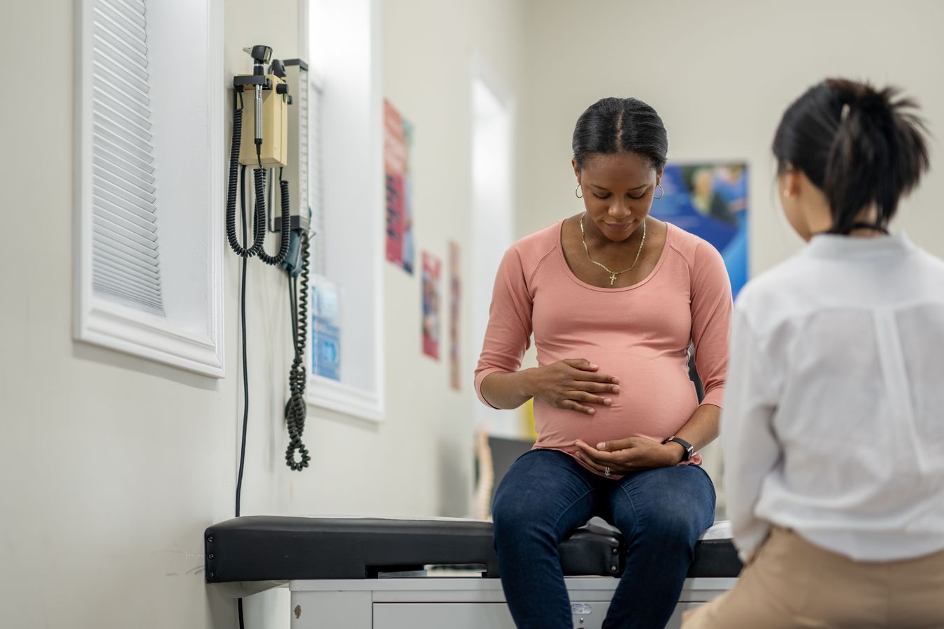 A pregnant woman sitting in a doctor's office across from a doctor
