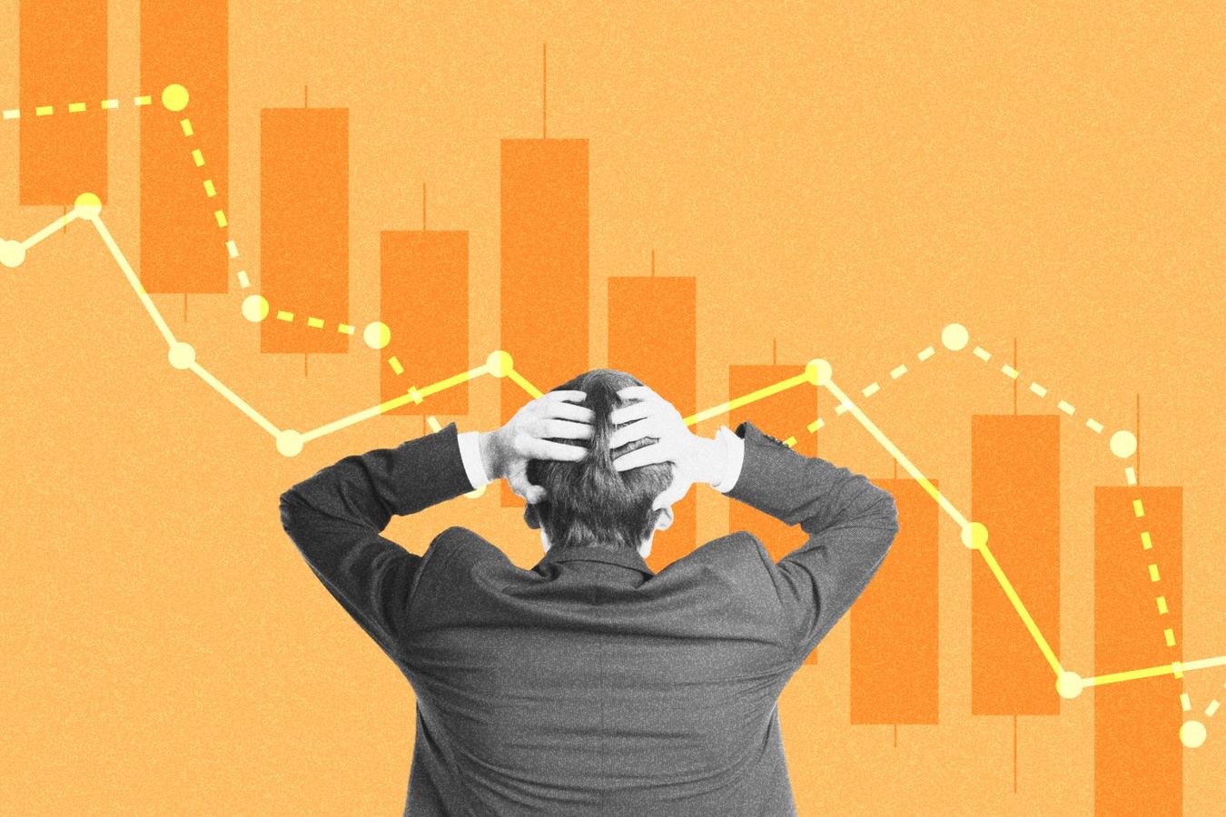 Stressed businessman holding head in hands in front of downwards trending graphs